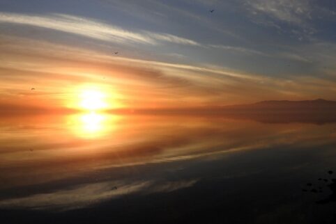 A yellow sun setting over a reflective lake